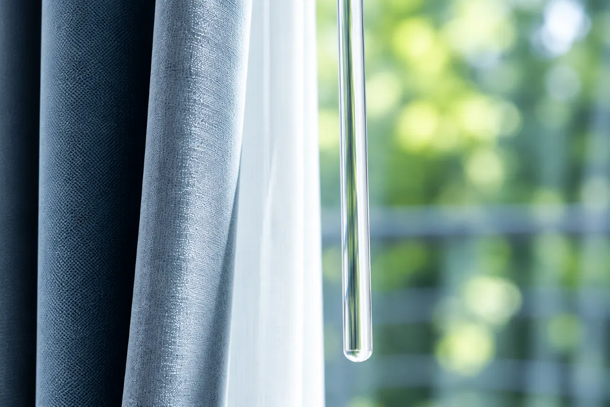 Close-up of grey blackout curtains with a white sheer curtain beside a window